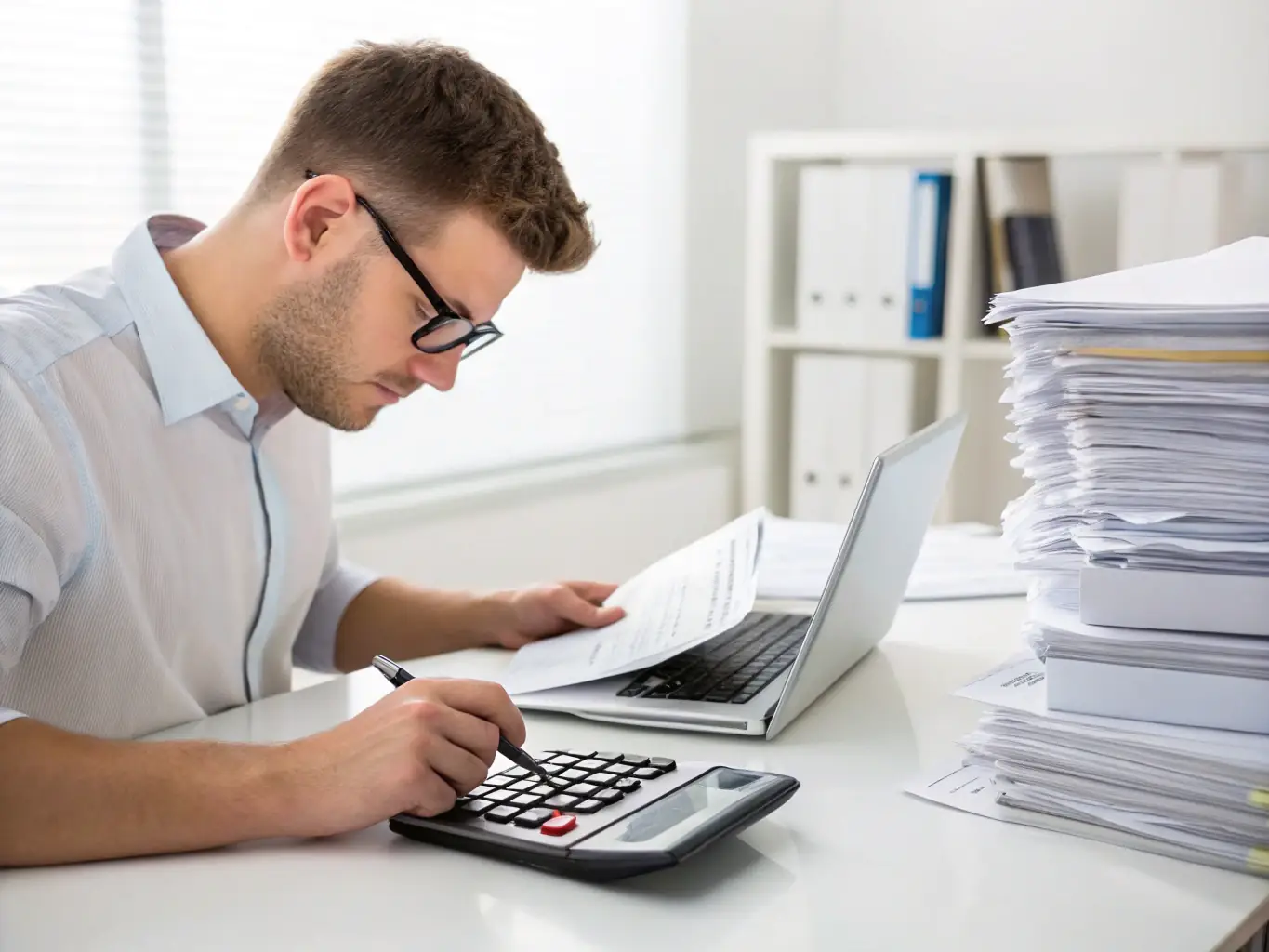 A person using a calculator to determine the best savings strategy while reviewing UK tax regulations on a laptop.